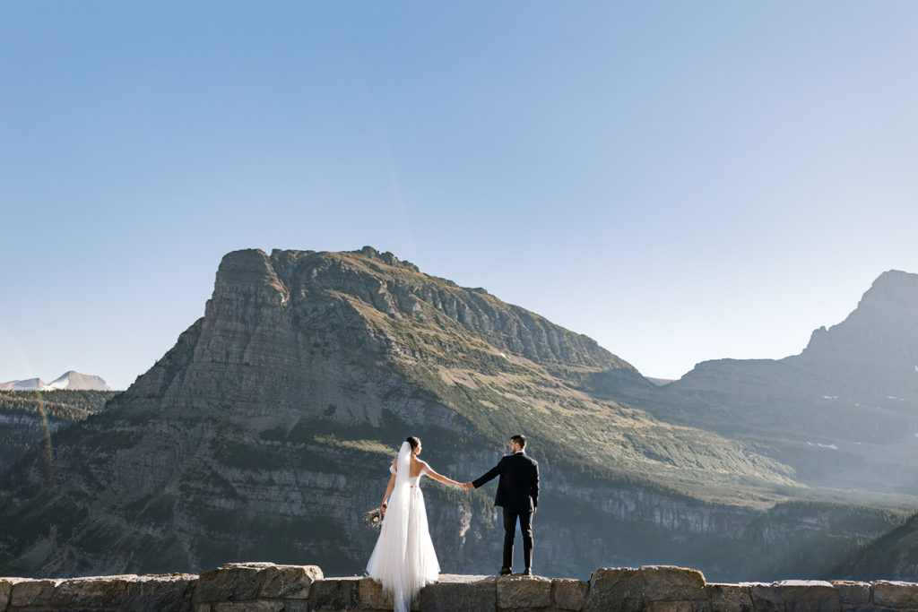 Husband and Wife holding hands in Glacier National Park after elopement