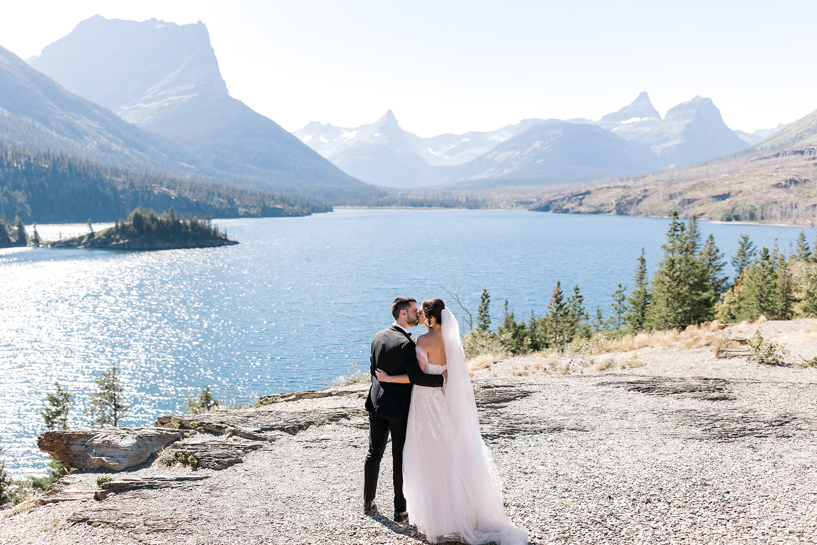 Bride and groom shares a kiss overlooking St Mary Lake at Sun Point in Glacier National Park